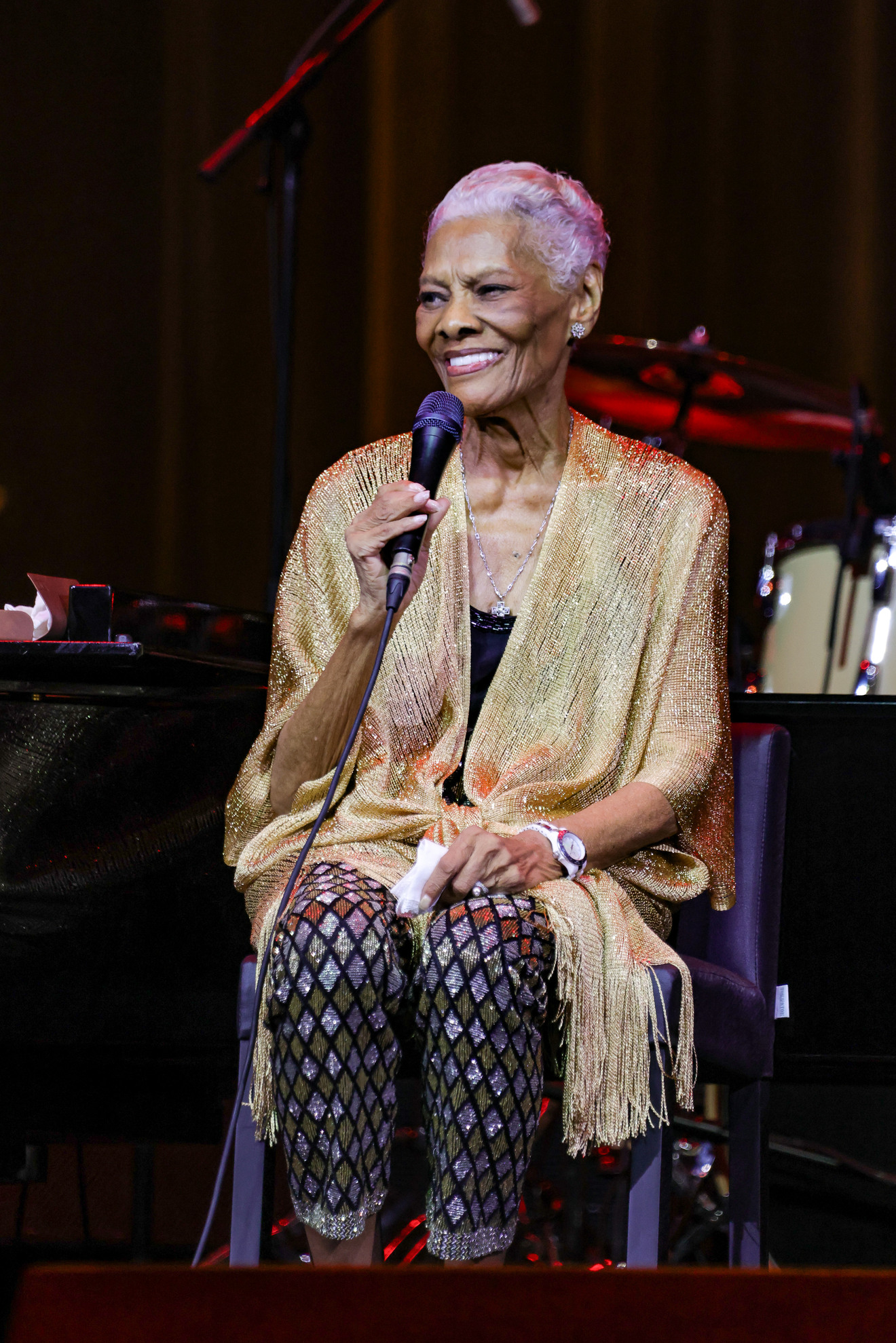 Dionne Warwick sentada e cantando durante o show de despedida no Vivo Rio